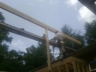 Carpenter setting a ridge beam over a new addition frame — Ice Dam Removal by Roofing Brothers in Imogene