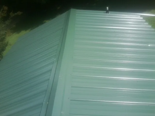 New green metal panels meeting at the ridge of a roof — Flat Roof Repair work by our crew in Imogene