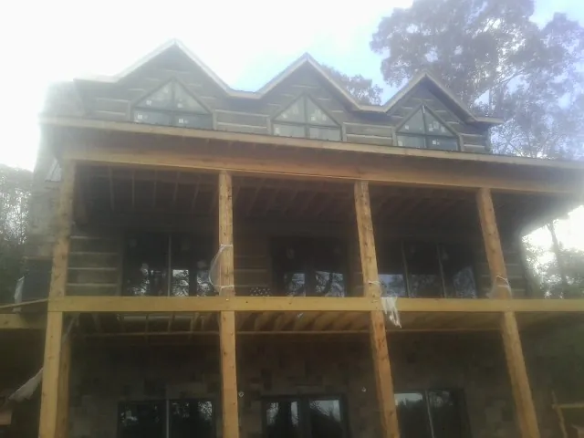 Dormers and porch framing on a large log home under construction — Roof Coating work by our crew in Imogene