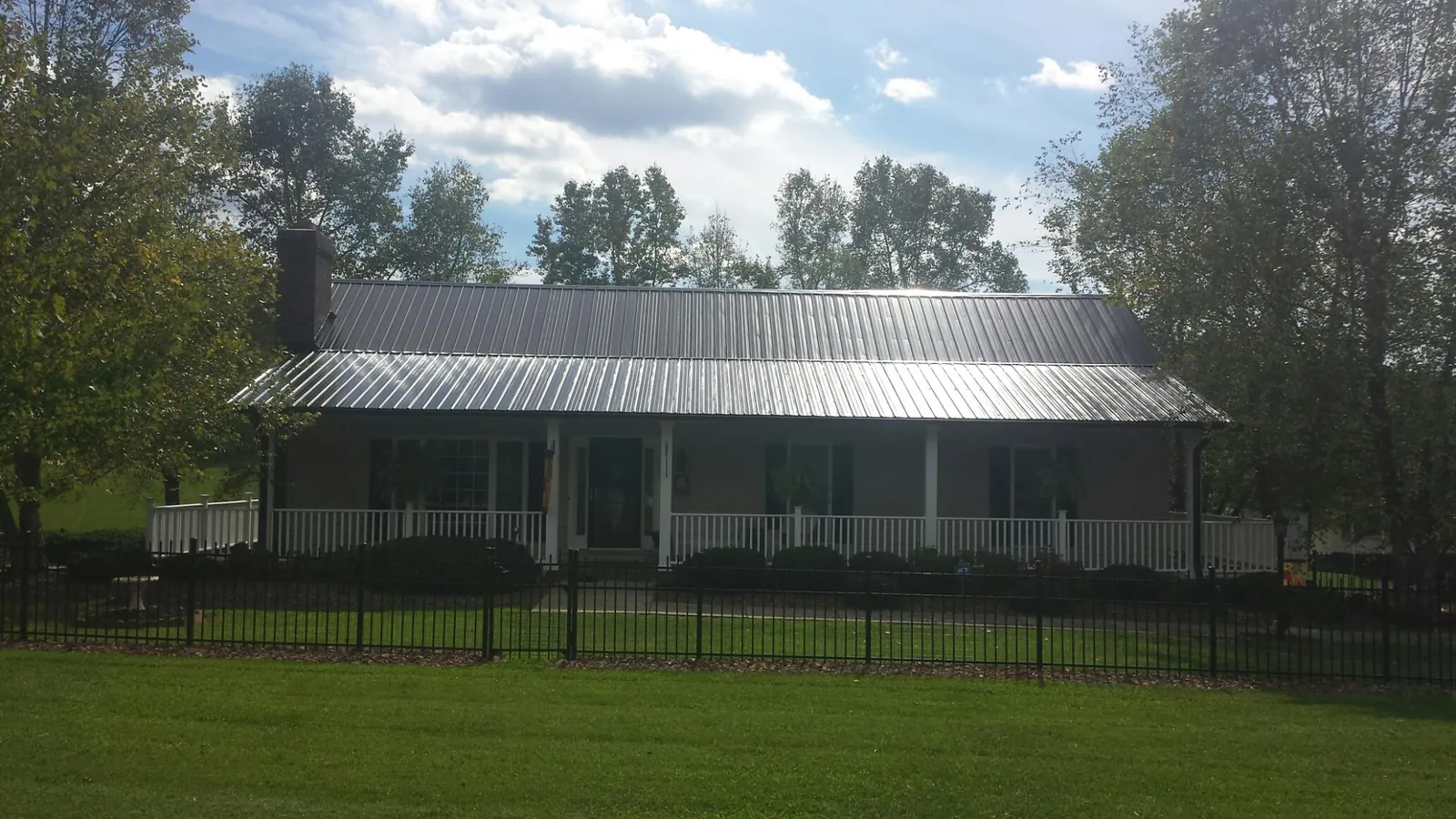 Gray metal roof on a brick ranch with a full width front porch — Gutter Guard Installation work by our crew in Imogene