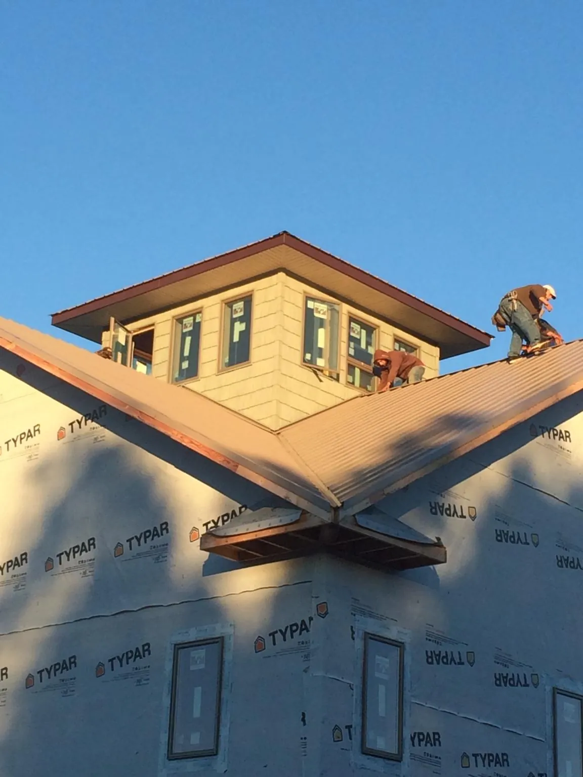 Roofers working around a rooftop cupola on a new metal roof at sunset — Roof Waterproofing in Imogene by Roofing Brothers